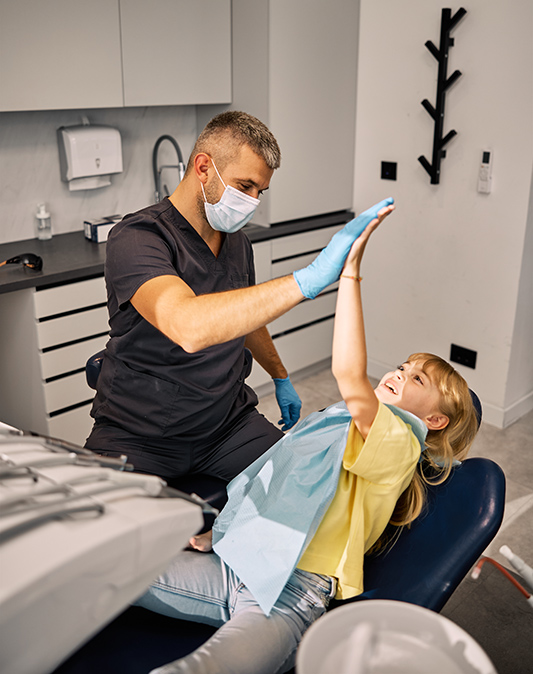 Smiling Dentist High-Fiving Young Girl in Clinic
