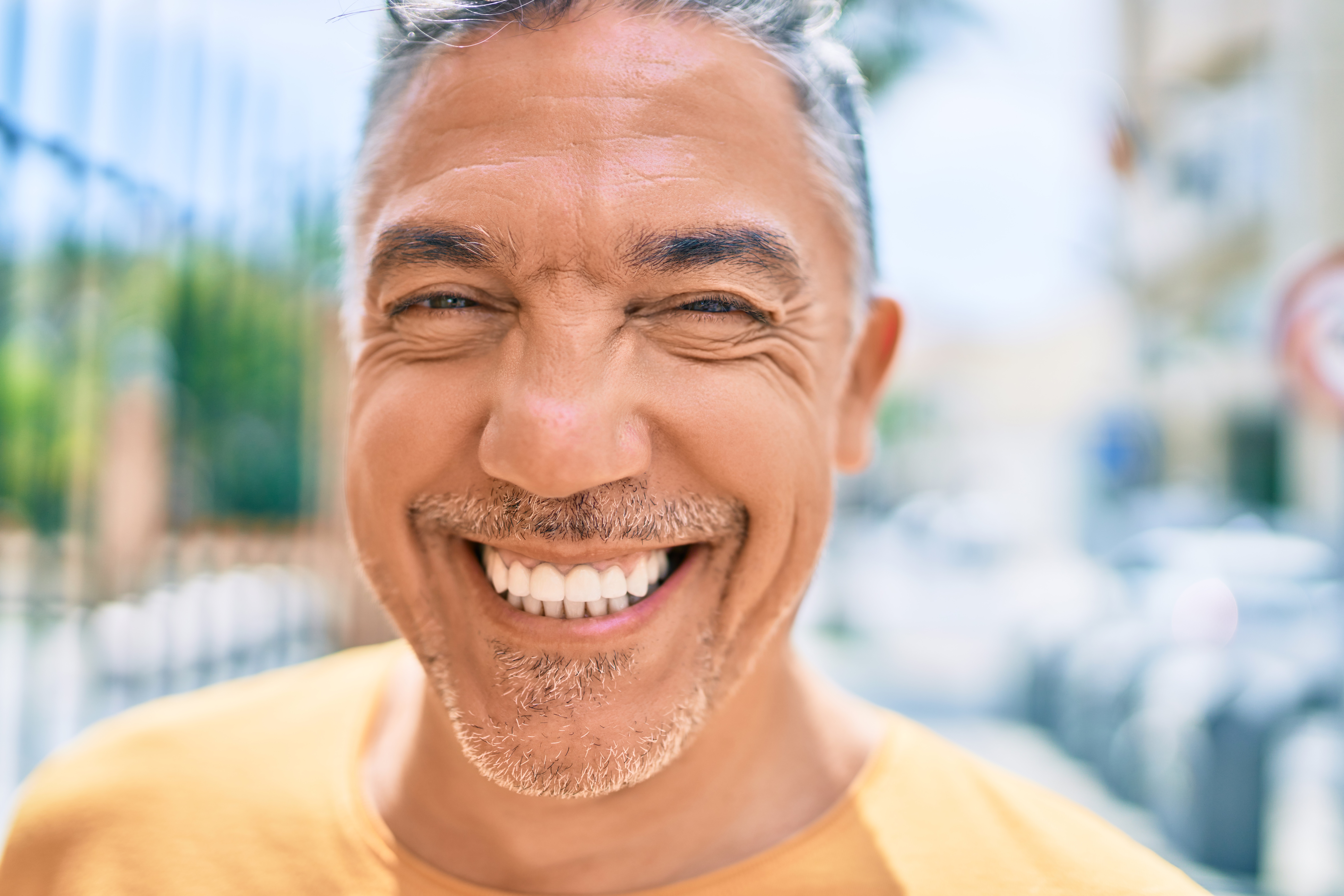 Middle age grey-haired man smiling happy walking at street of city. adult dental medicaid